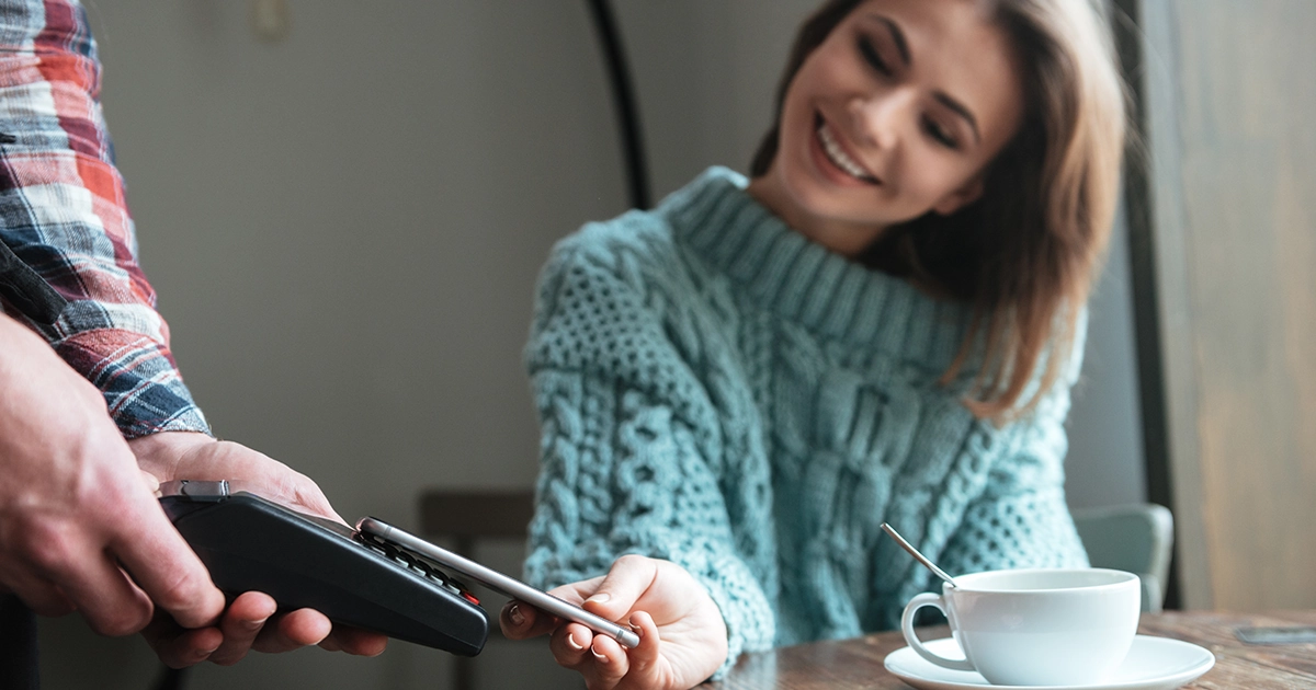 Woman paying with her phone at a café card machine