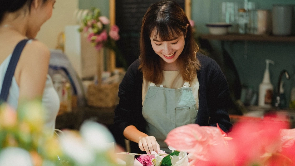 Smiling florist wrapping a bouquet for a customer in her flower shop