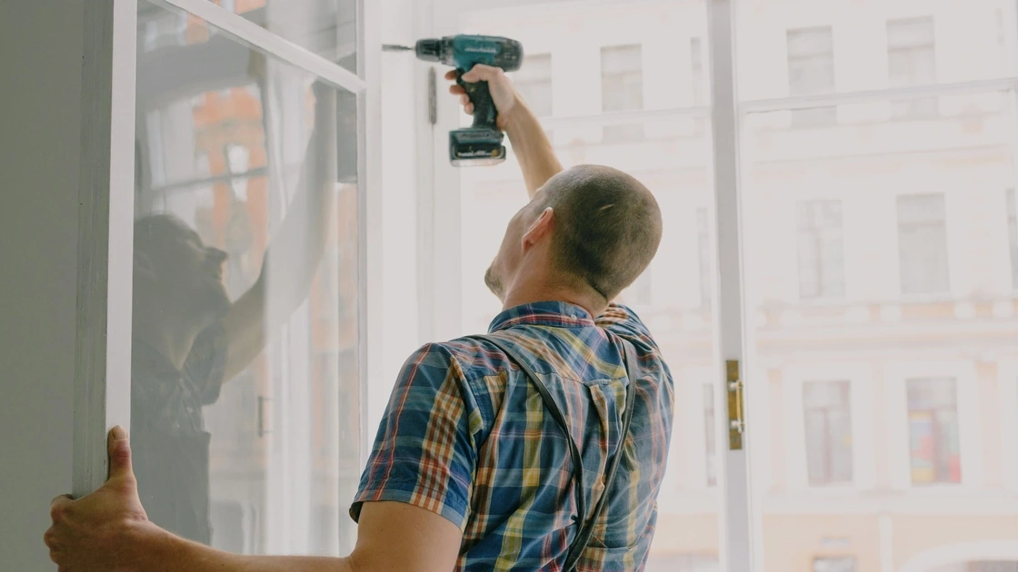 Handyman using a cordless drill to install a window frame