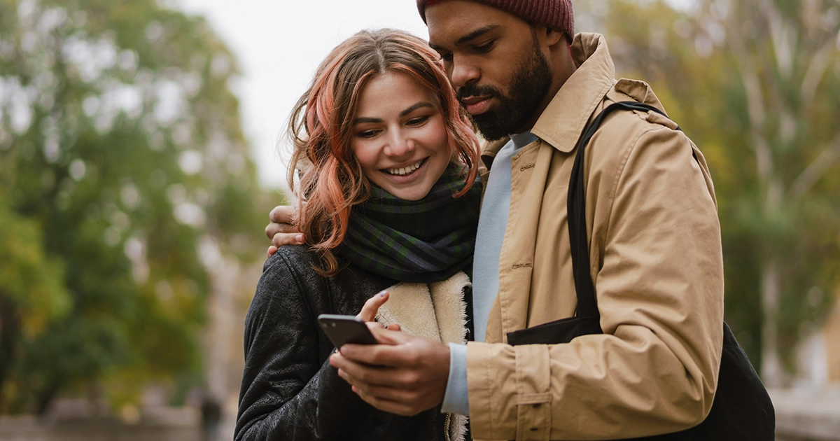 Smiling couple looking at a phone together outdoors